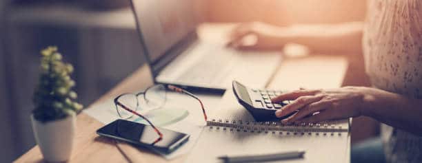 woman's hand on a work station with her hands on a laptop and calculator- QuickBooks concept