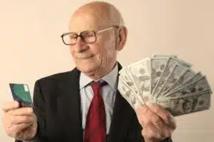 an older man holding a credit card on the right hand and cash on the left hand