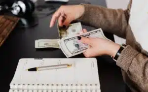 women counting money to pay the credits listed on the notebook